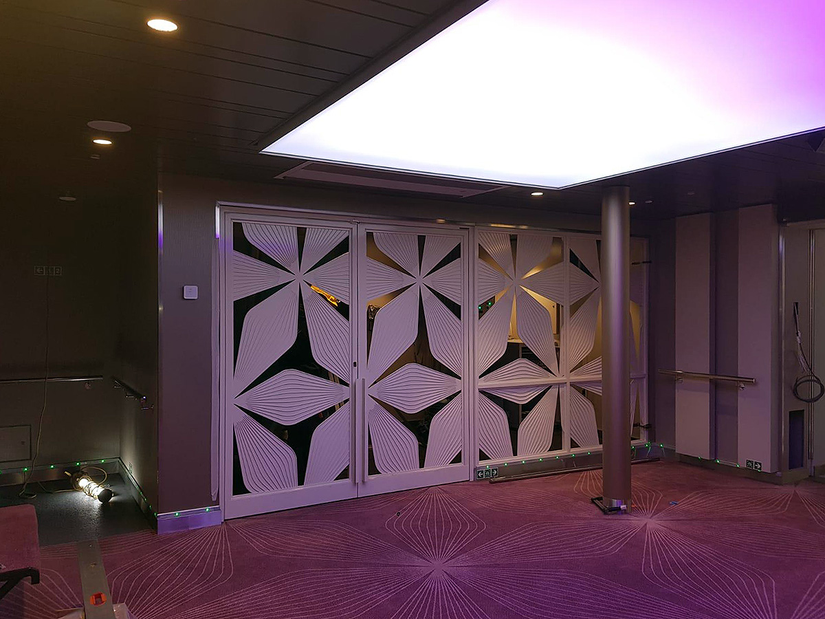 Interior view aboard Tallink Megastar, showcasing elegant decorative glass sliding doors with a modern floral motif. Surrounded by a stylish purple-toned carpet and soft ambient lighting, the space exudes a luxurious, contemporary feel. Ideal for highlighting premium ferry interior design, architectural glasswork, and cruise ship aesthetics.